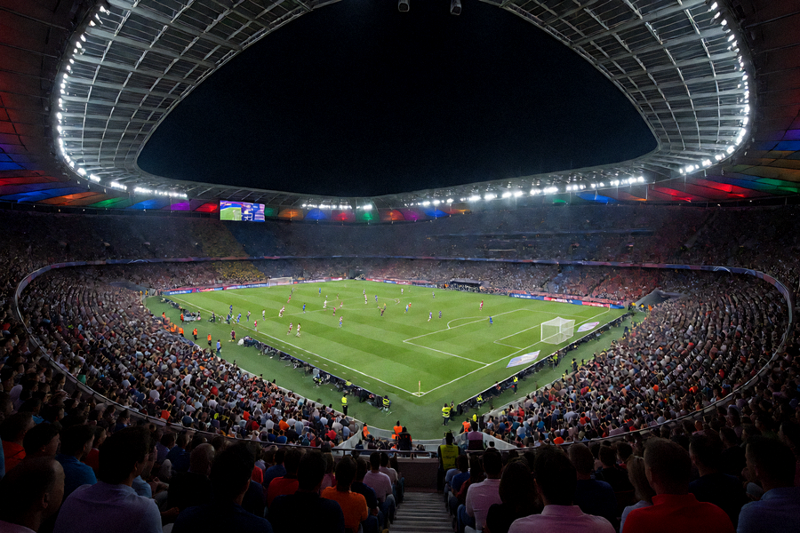 夜晚灯光下的体育场全景，观众席座无虚席的足球比赛现场